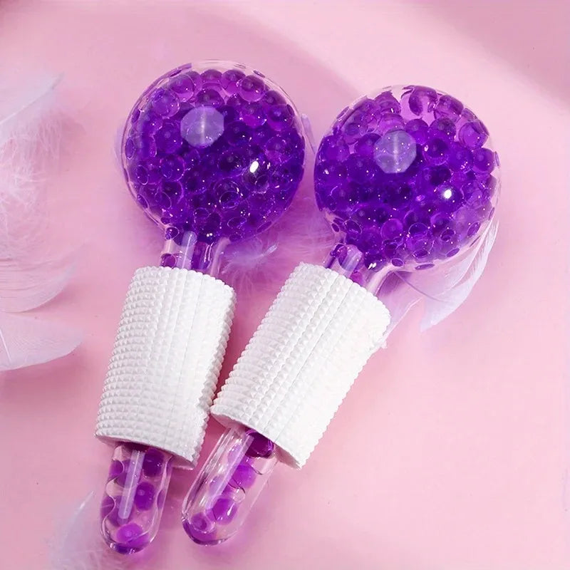 Two purple, glittery facial massage globes with white textured grips, set against a soft pink background.