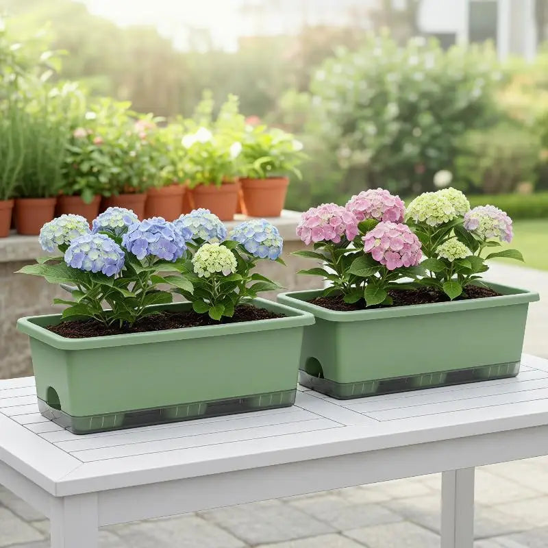 Green self-watering planter box pair with blooming flowers on an outdoor patio table