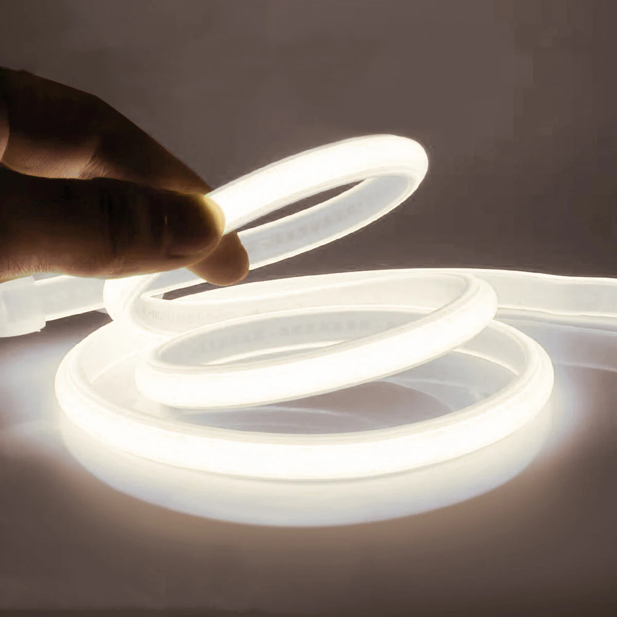 Flexible neon LED tape light strip with warm white glow, held above surface