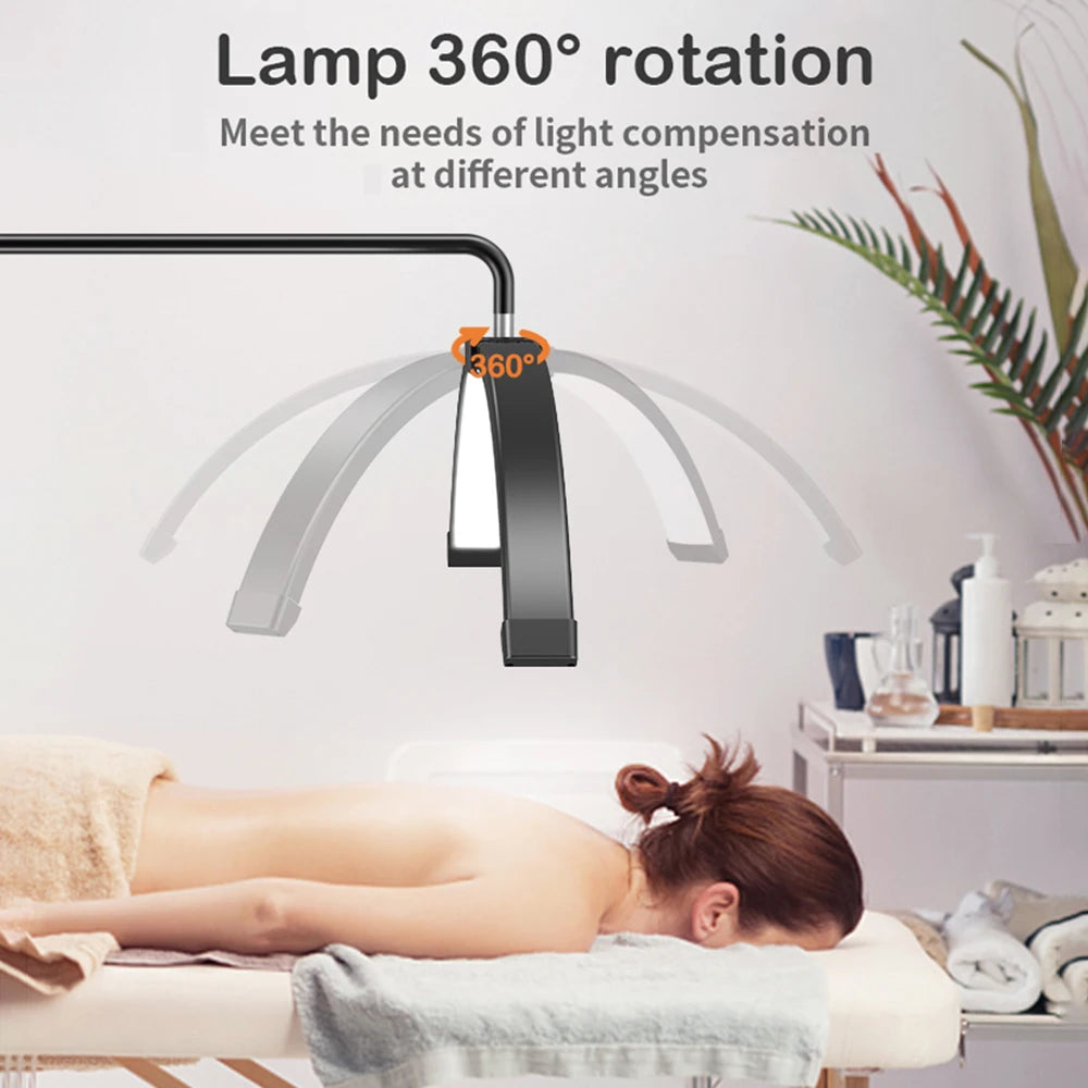 Black arc-shaped lash and beauty lamp with a rotating head, suspended above a massage table for adjustable lighting.