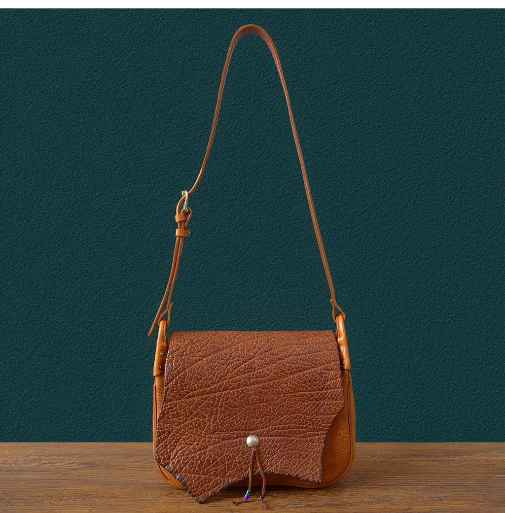 Vintage tan genuine cowhide leather messenger bag with textured flap, adjustable shoulder strap, and casual design.