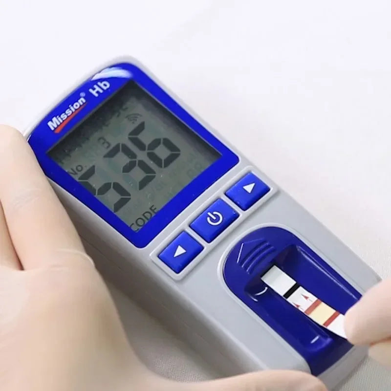 Mission Hb hemoglobin analyzer device with digital screen and test strip for portable anemia testing at home.