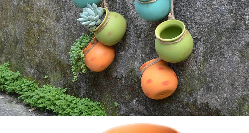Group of hanging ceramic planters with succulents in green and orange