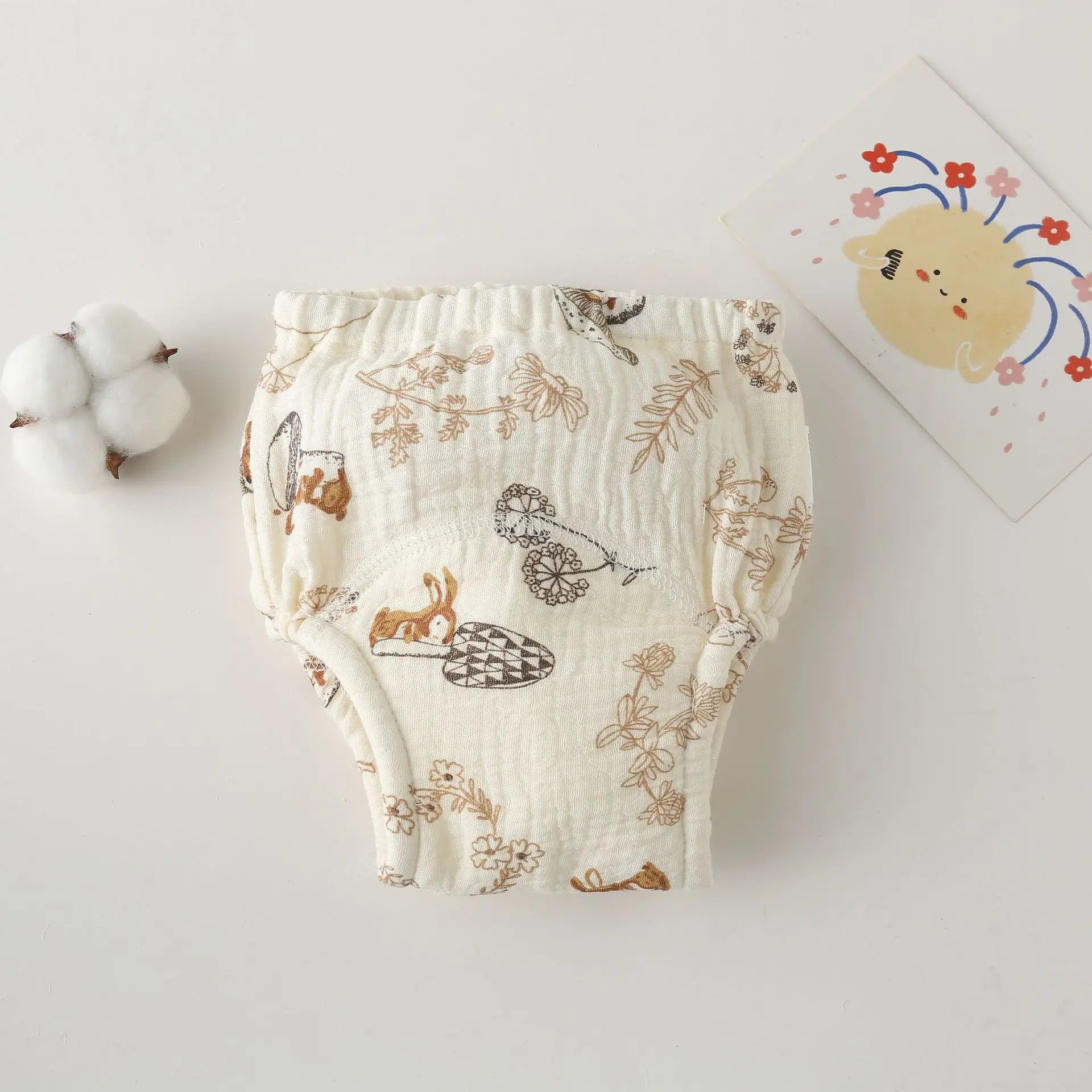 Muslin cloth baby training diaper with floral and forest animal print on cream background.