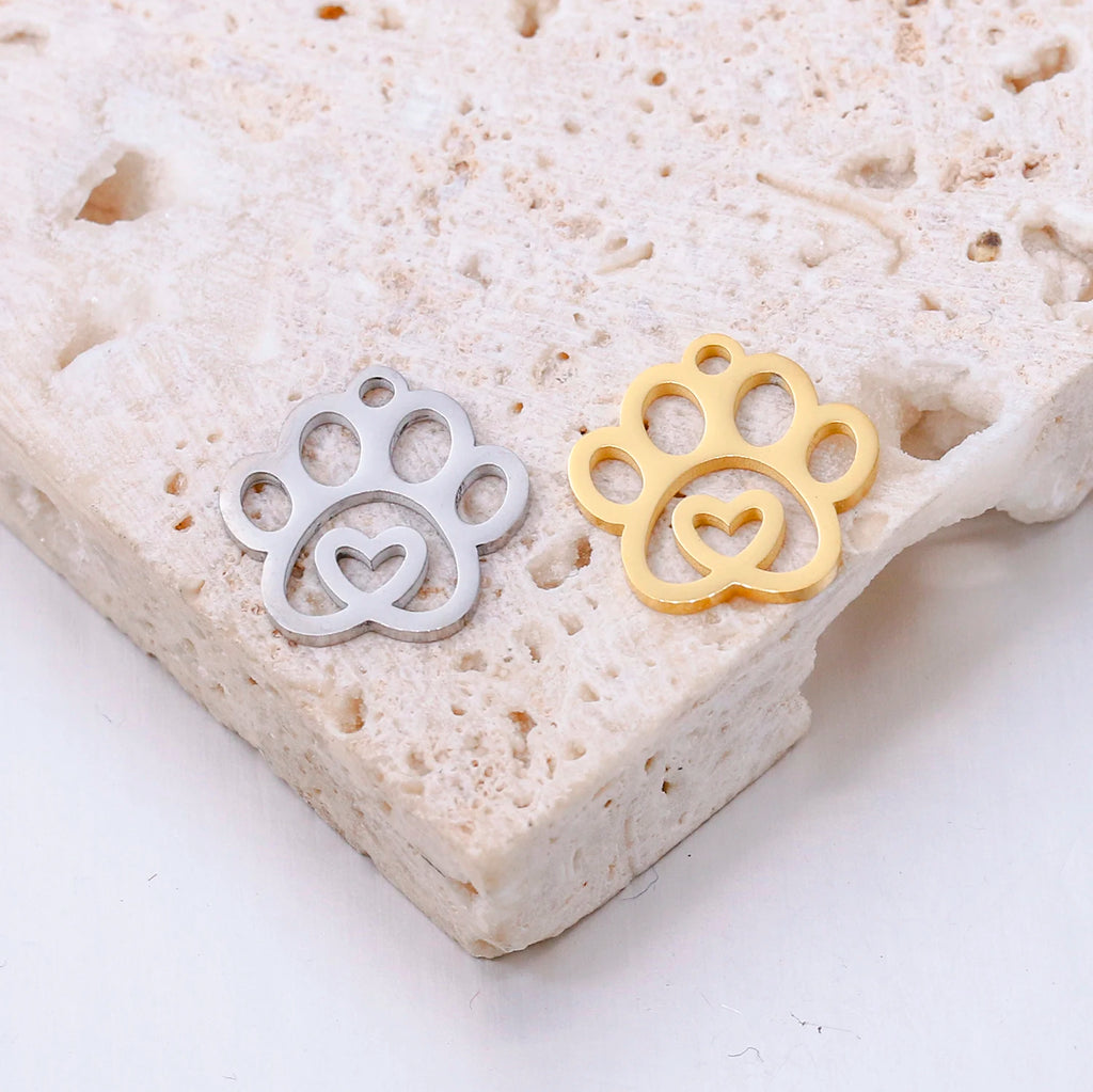 Gold and silver stainless steel dog paw print charms with heart cutouts for DIY pet jewelry and necklace making.