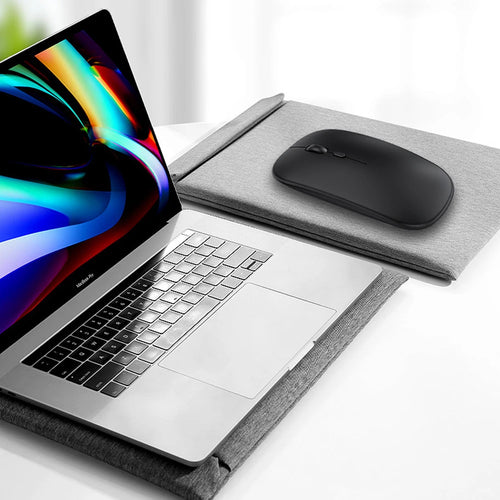 Sleek, black, low-profile wireless mouse with a scroll wheel and DPI button, sitting next to a laptop on a gray pad.