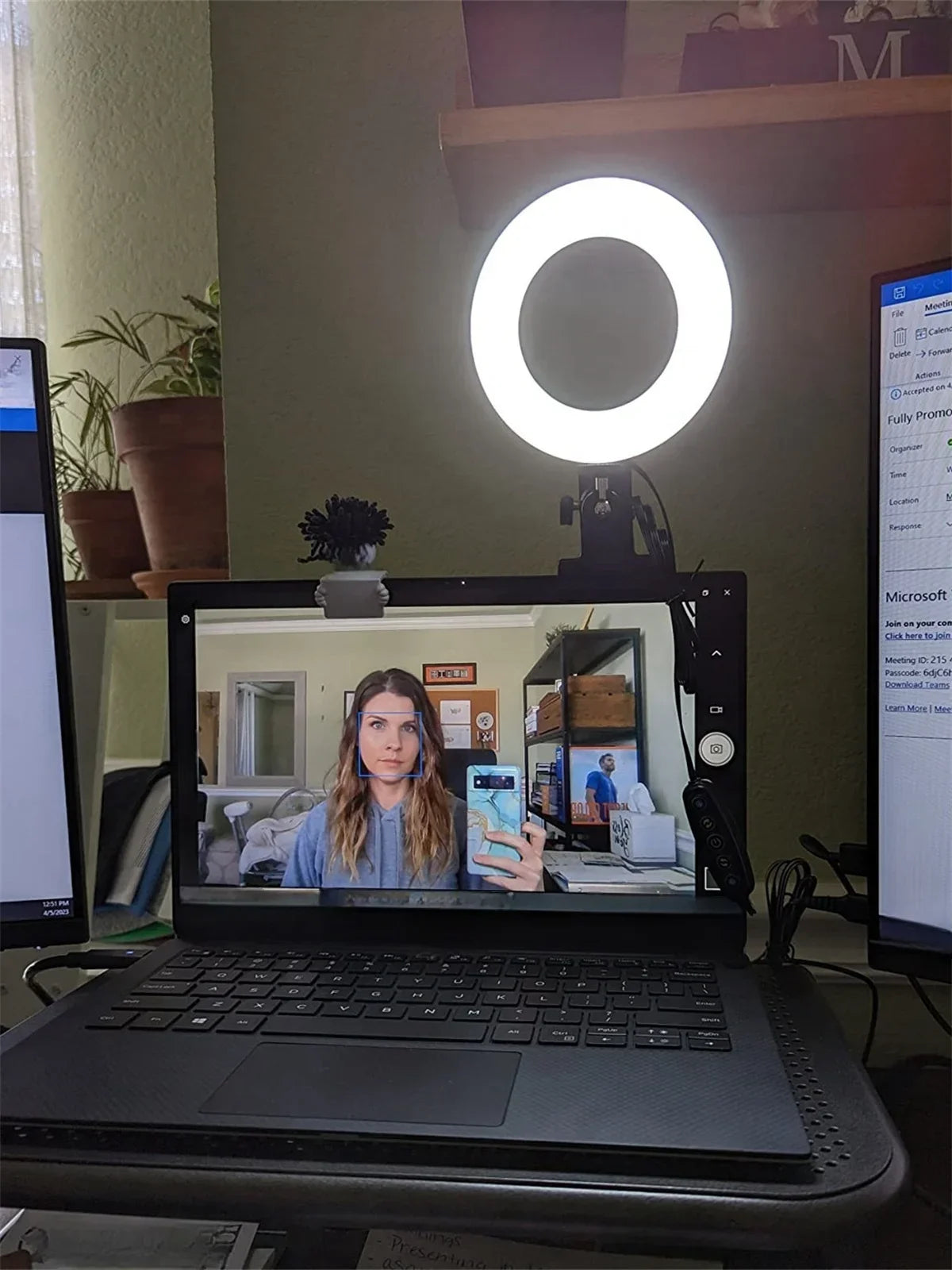 A white, circular LED ring light mounted to the top of a laptop screen to provide illumination for video calls.