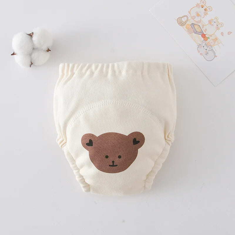 Cream-colored baby training pants with a cute brown bear face design. Comfortable cotton diaper cover for toddlers.