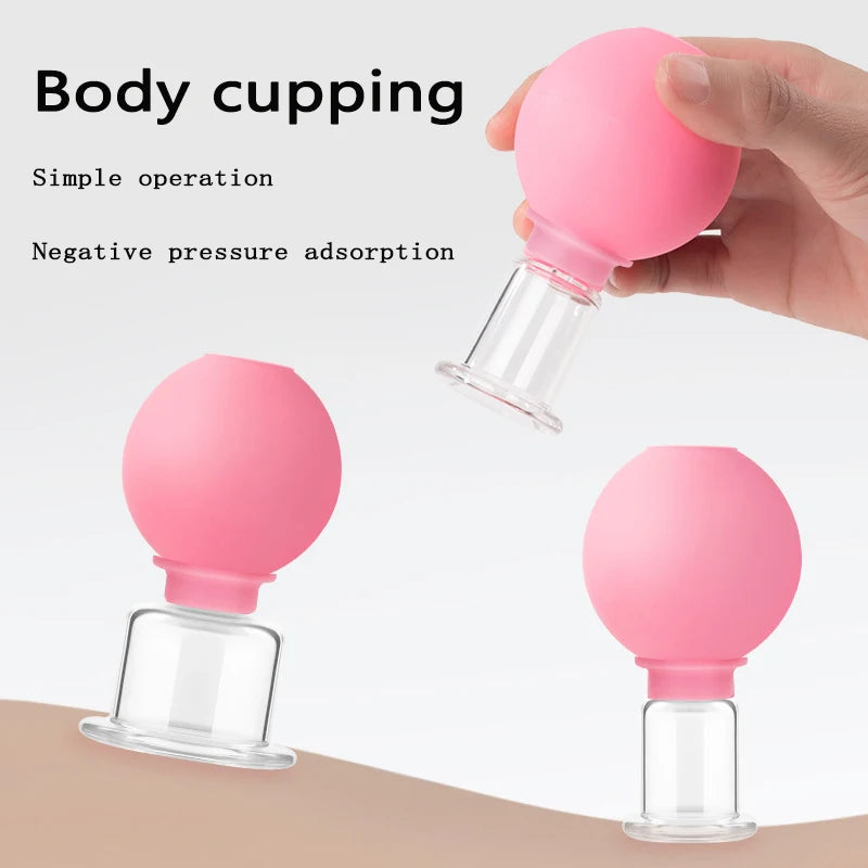 Three pink rubber bulb facial cupping devices with clear glass suction heads, one held by a hand.