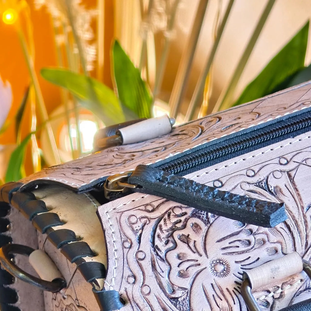 Luxury hand-tooled floral leather weekender trunk bag with black stitched edges and sturdy zipper detail.