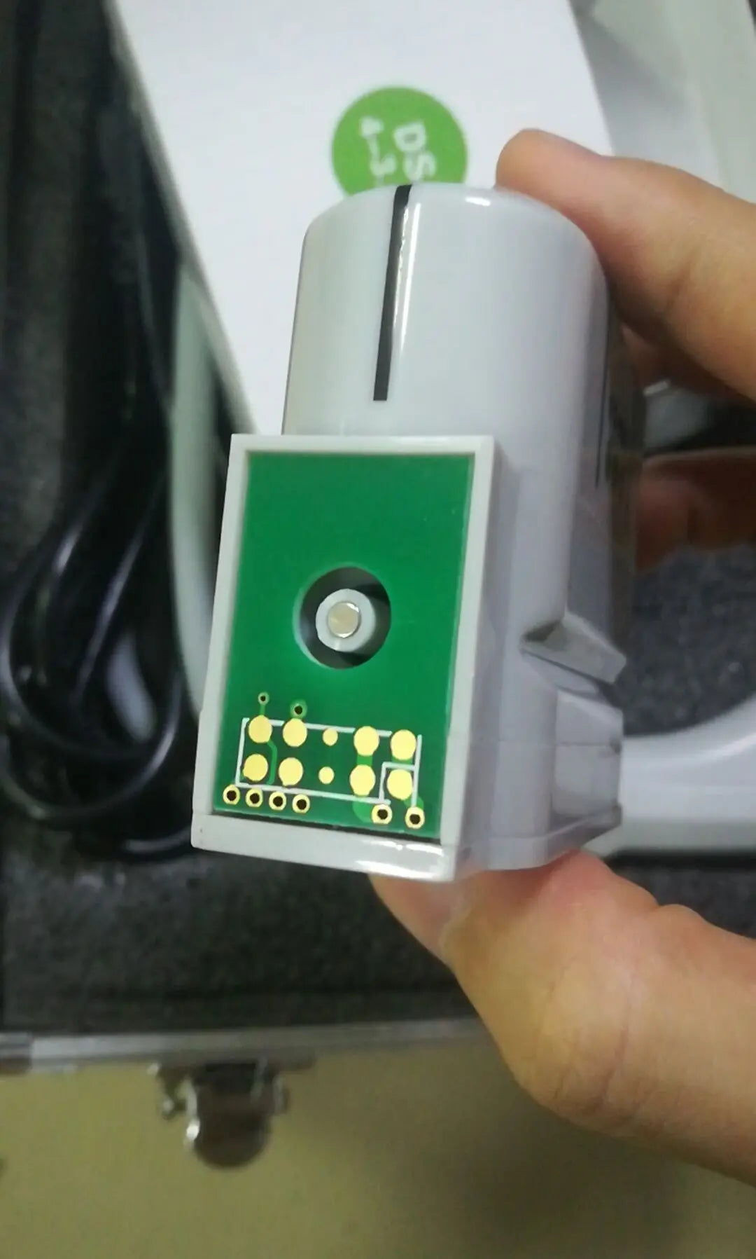 Close-up of a grey HIFU machine replacement cartridge with a green circuit board interface and gold contact pins.