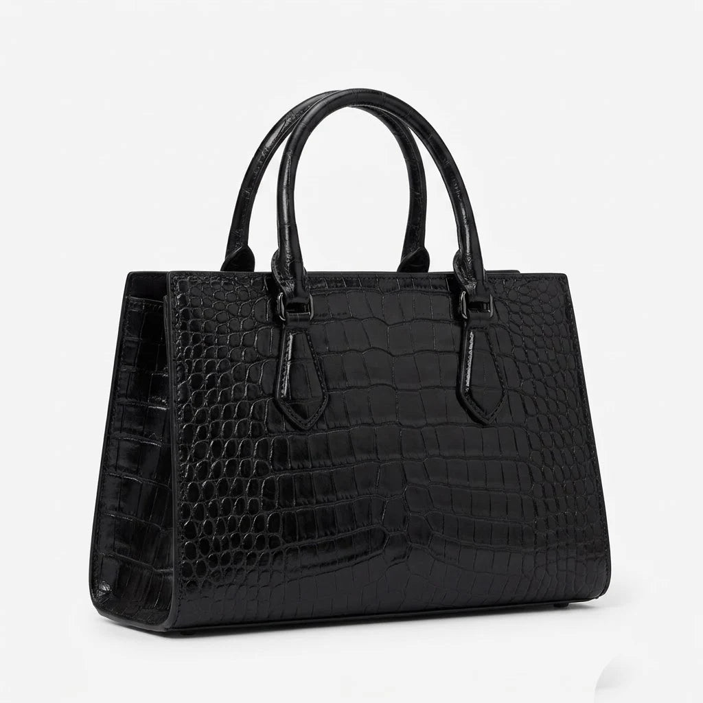 Black vintage-style alligator embossed leather designer handbag with dual top handles and structured silhouette.