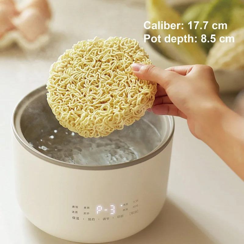 1.5L electric rice cooker steaming noodles in the inner pot, hands holding the noodles