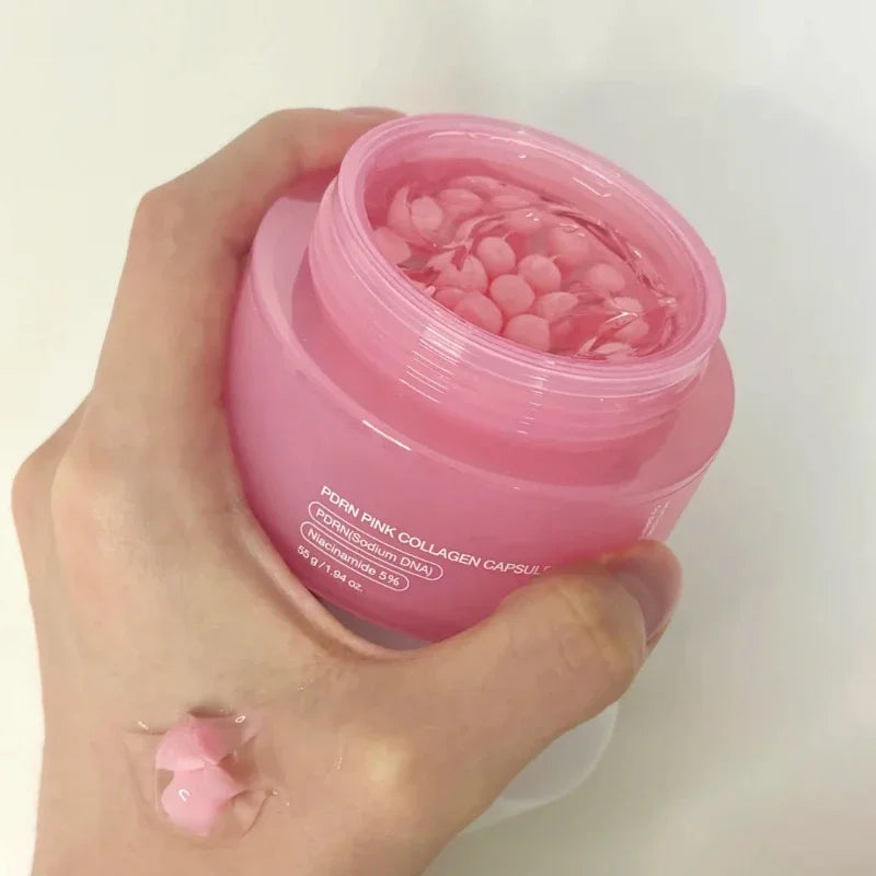 A hand holds an open jar of pink PDRN collagen capsule cream, with a dollop of the product on the skin.
