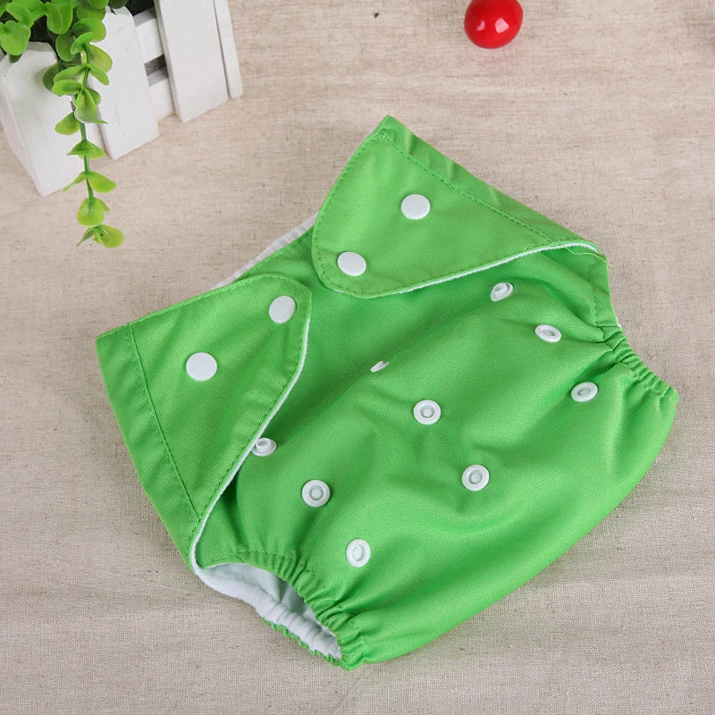 Green reusable cloth diaper with white snap closures for adjustable baby care fit.