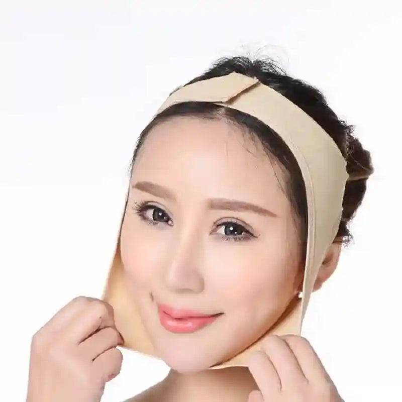 A woman wears a beige elastic face-slimming bandage wrapped under her chin and secured over the top of her head.
