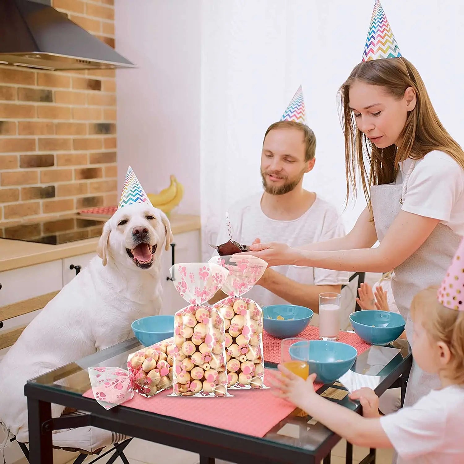 Clear cellophane treat bags with pink paw prints for dog birthday party favors, heat-sealable for snacks or candies.