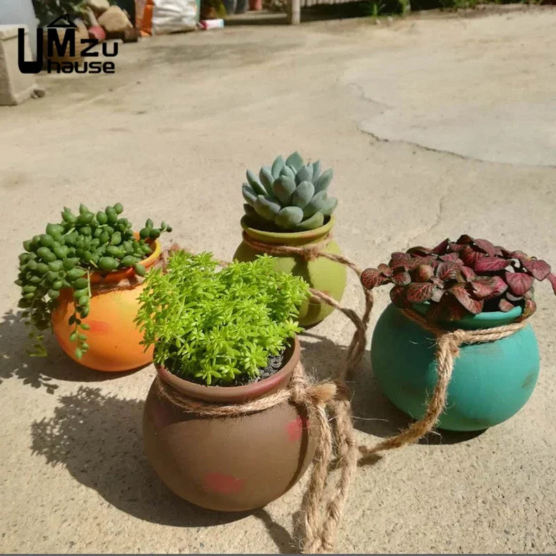Four hanging ceramic planters with succulents in orange, green, and gray tones