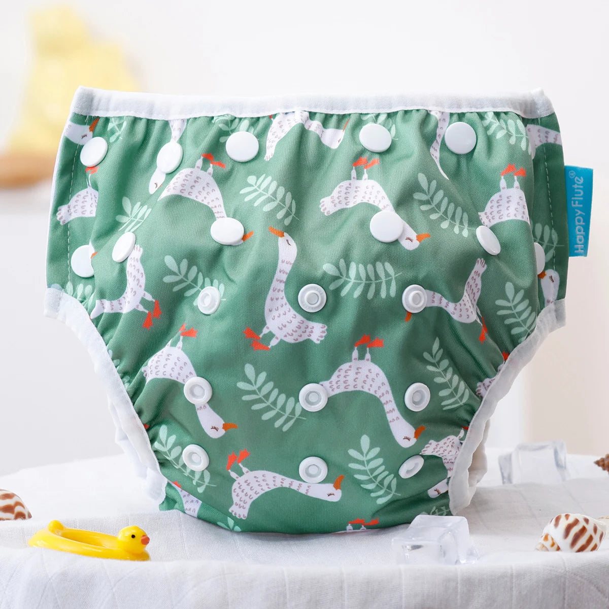 Happy Flute reusable cloth baby diaper in green with white goose and leaf pattern and adjustable snap closures.