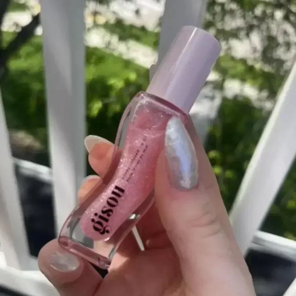 Gisou moisturizing pink glitter lip oil in a clear bottle for shiny, hydrated lips and reduced lip lines.