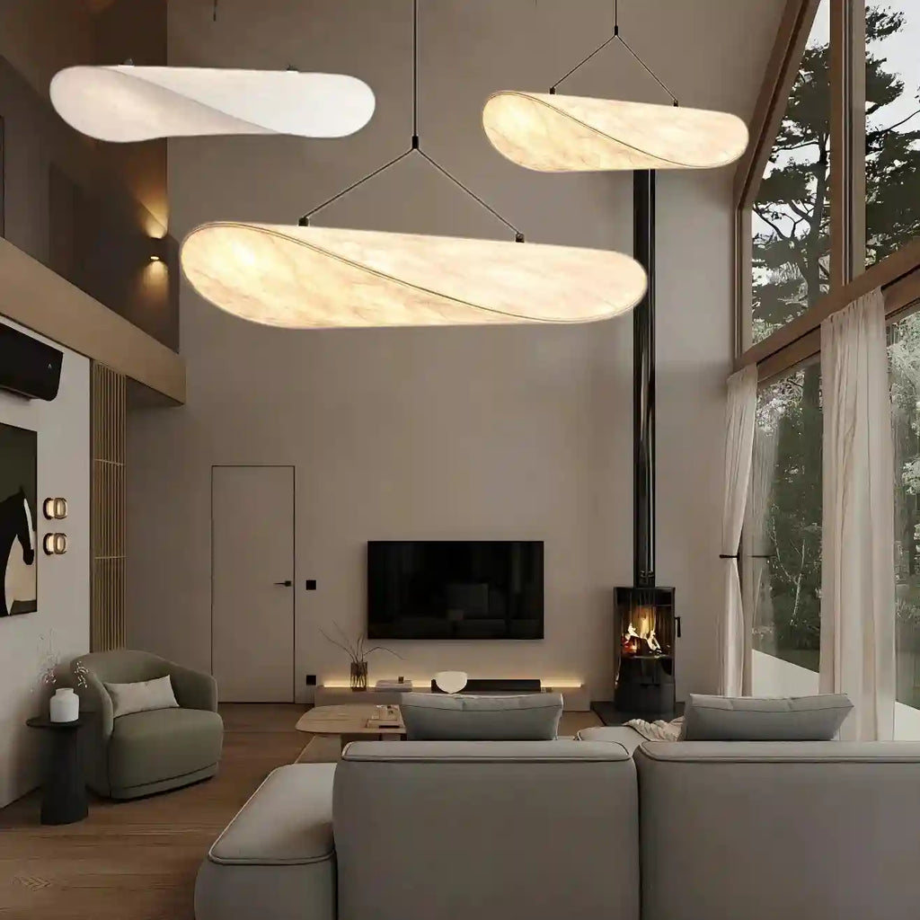 Long, curved pendant lights with marbled fabric shades, suspended by thin wires for ambient indoor lighting.