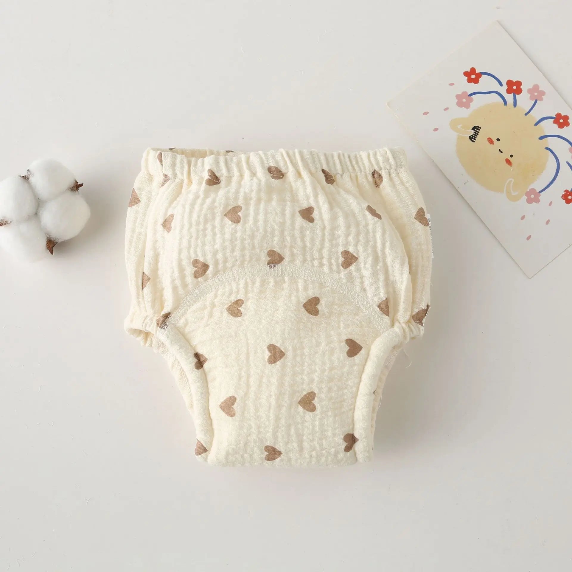 Cream-colored cotton baby training diaper with brown heart print, gentle absorbent baby care underwear.