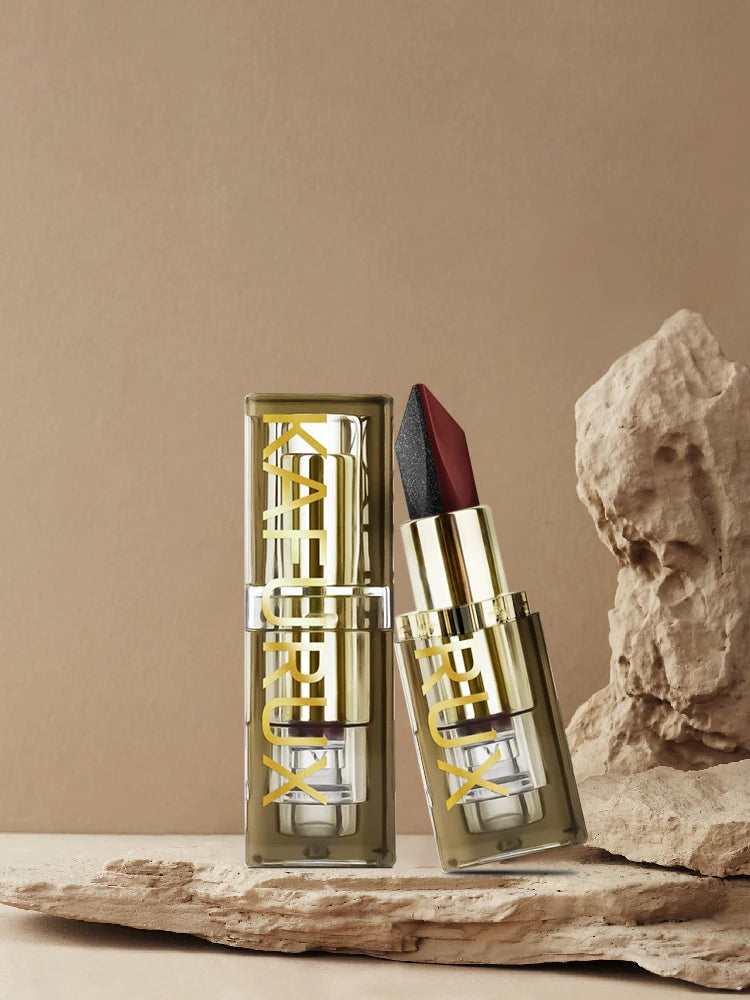 Two-tone lipstick with glitter black and matte red rose shades in a gold case, standing on a stone texture background.