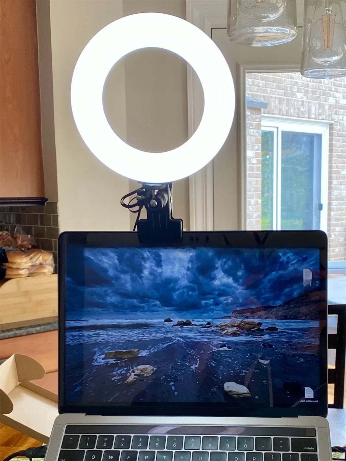 Circular LED ring light in a black plastic clip mount, attached to the top of a laptop screen for video lighting.