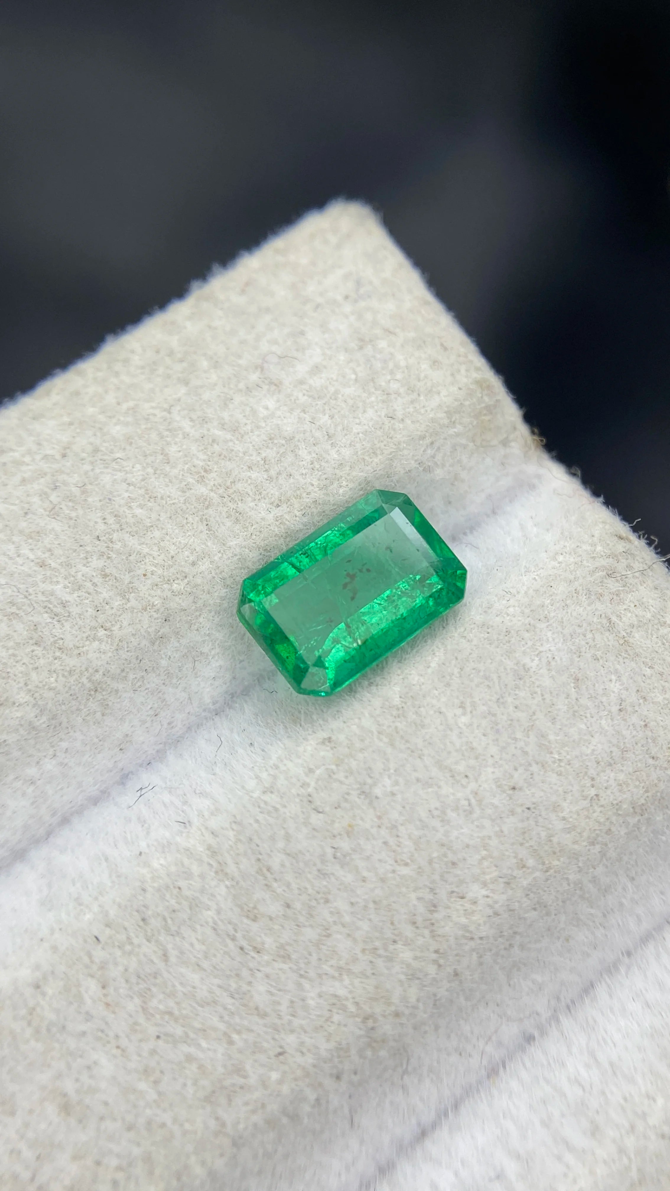 Green emerald-cut gemstone with octagon facets, loose natural stone on display.