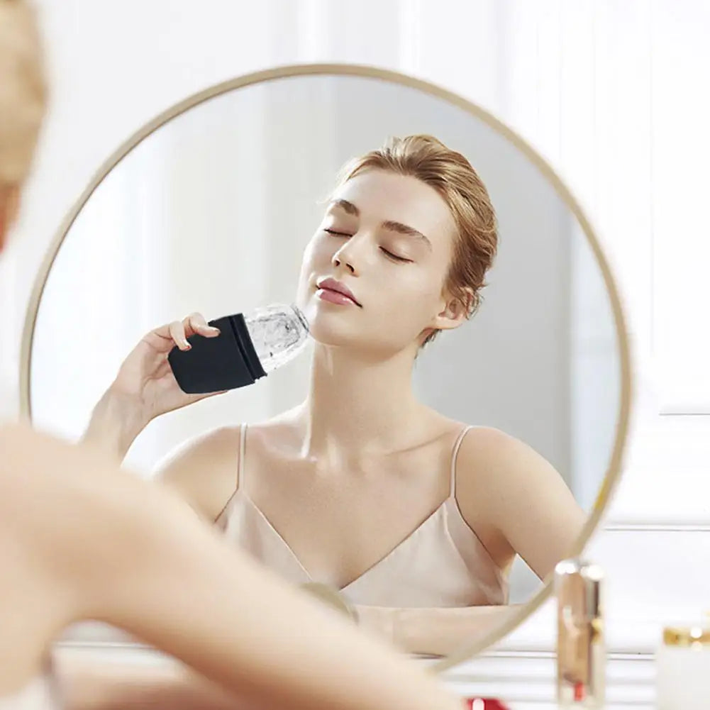 A person looking in a mirror and massaging their neck with a black-handled reusable ice face roller.