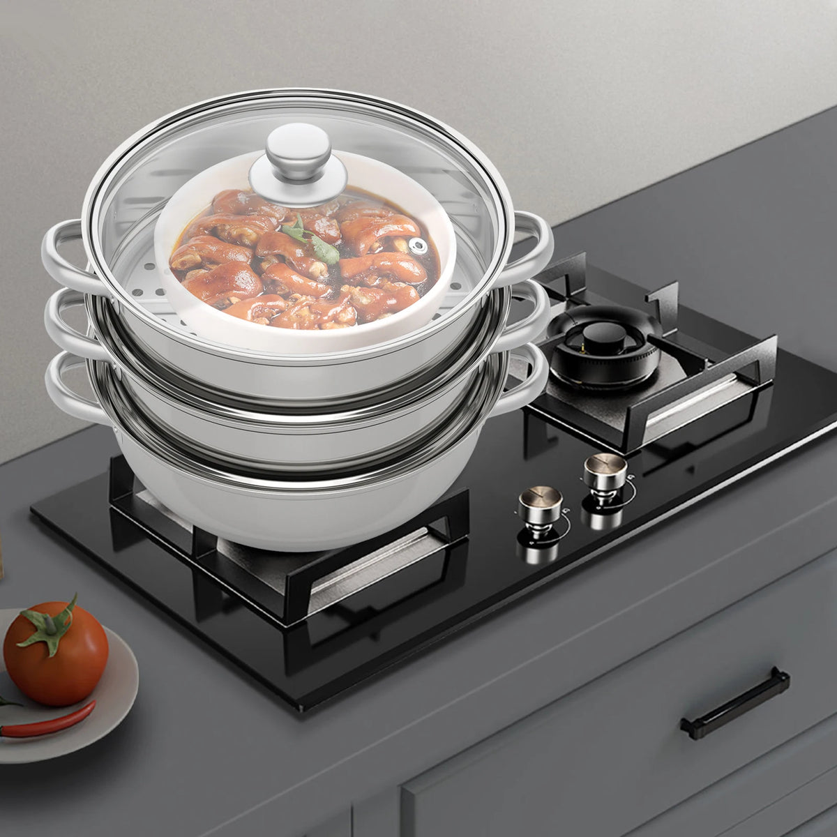 3-tier stainless steel steamer pot on black stove with lid and side handles.