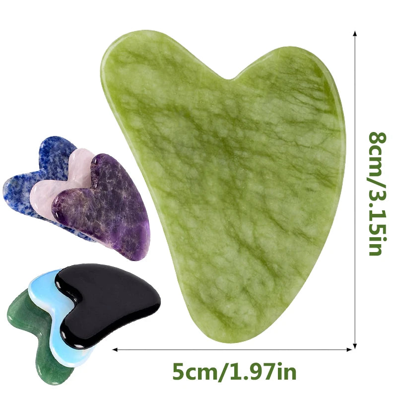 Heart-shaped facial gua sha tools made of multi-colored polished gemstones, including green jade, purple, and black.