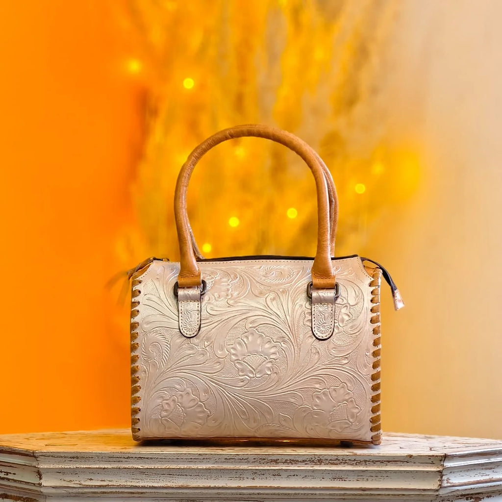 Beige leather mini speedy bag with floral hand-tooling, stitched sides, and tan handles. Designer travel handbag.