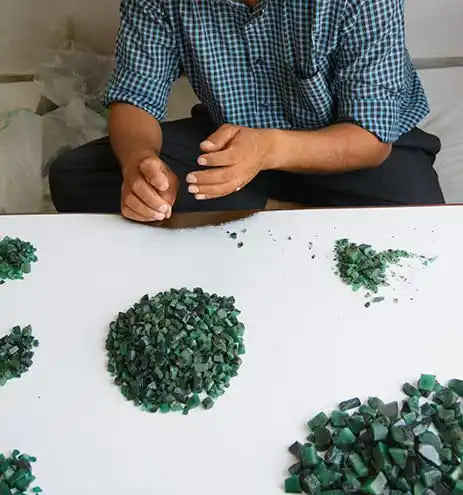 Green emerald gemstone chips scattered on a white surface