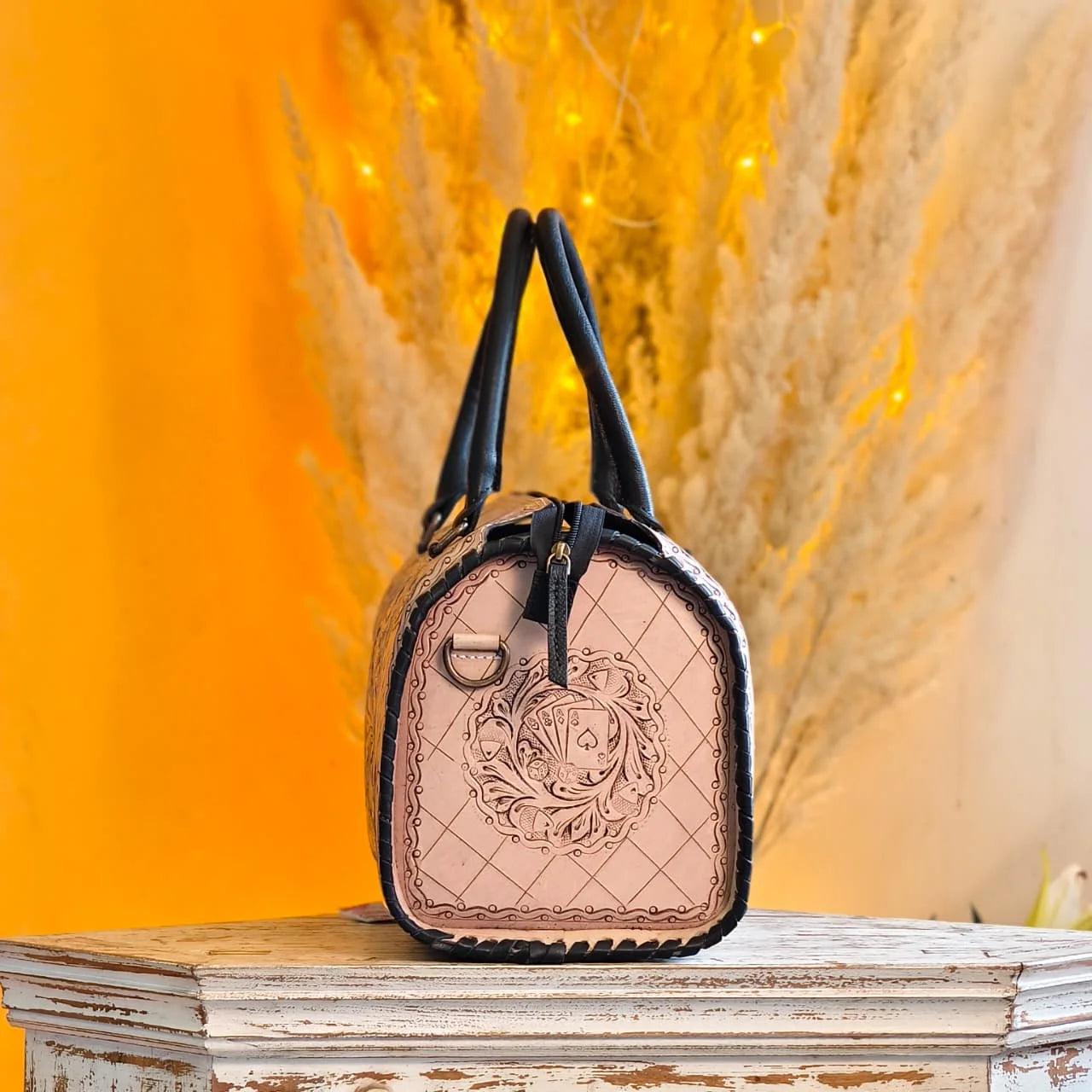 Luxury hand-tooled leather weekender duffle bag, beige with black trim, floral and playing card carvings, trunk style.