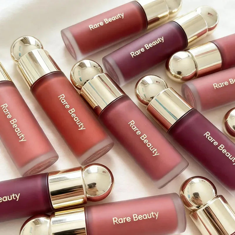 Rare Beauty Soft Pinch Liquid Blush collection in various matte shades with gold caps on a white background.
