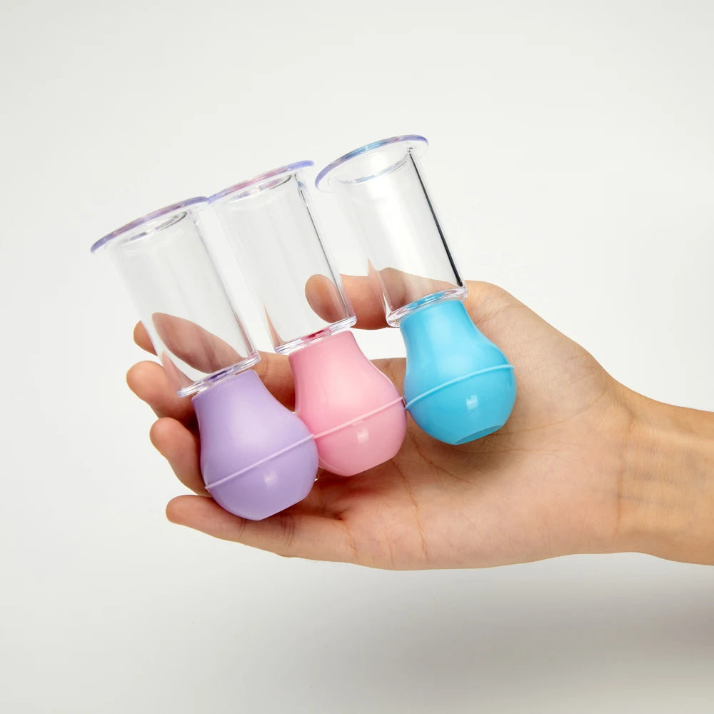Hand holding three colorful, clear vacuum facial massage cups for skin lifting, anti-cellulite, and scraping therapy.
