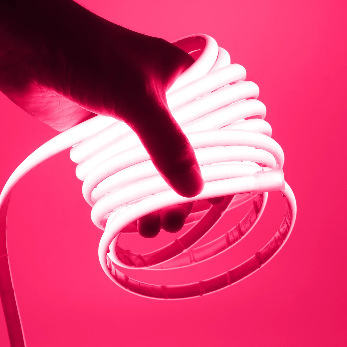 Waterproof COB LED neon strip light glowing pink-magenta, held in hand