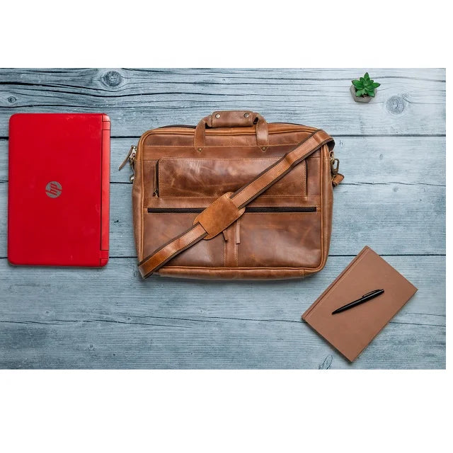 Tan genuine leather business briefcase with shoulder strap, laptop messenger style for men, laid on a wooden desk.