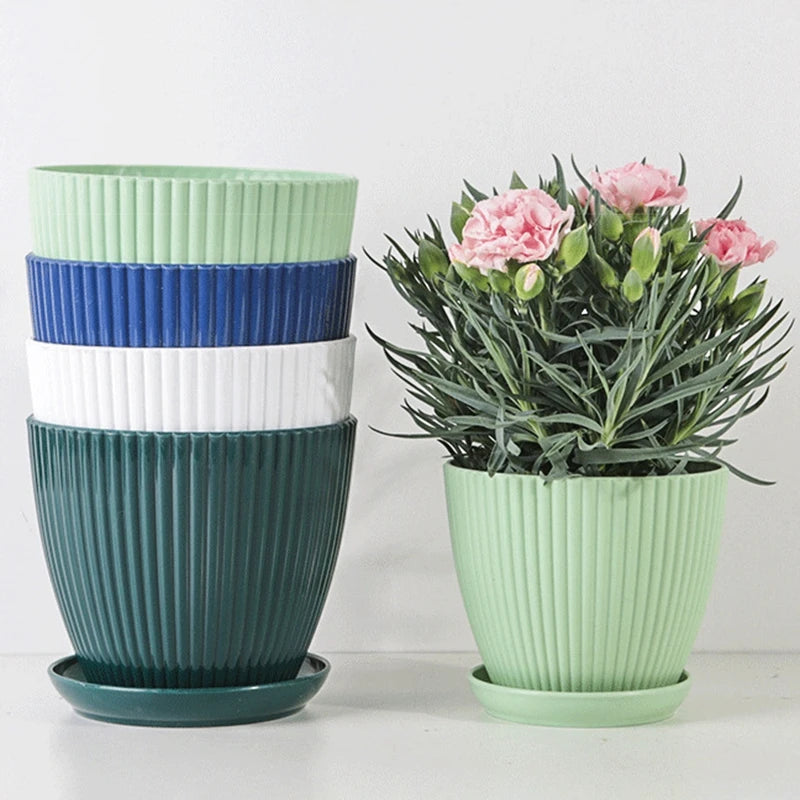 Ribbed plastic plant pots with tray in mint green and dark teal, shown with flowers