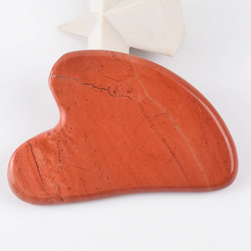 Heart-shaped red stone Gua Sha facial massage tool with natural veining and a smooth, polished finish.