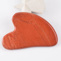 Heart-shaped red stone Gua Sha facial massage tool with natural veining and a smooth, polished finish.
