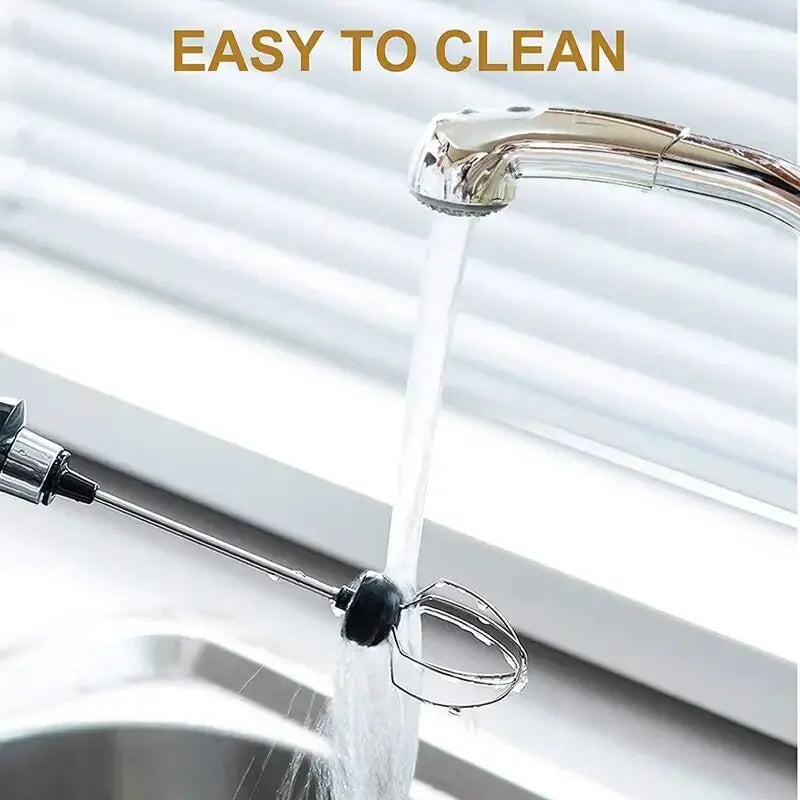 Rinsing a stainless steel handheld electric milk frother whisk under a kitchen sink faucet for easy cleaning.