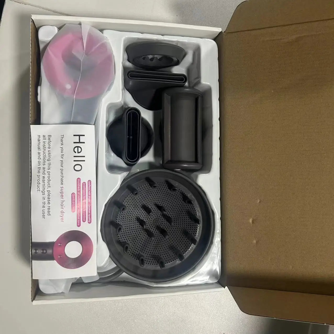 Pink and grey 5-in-1 ionic leafless hair dryer set with diffuser and styling attachments in product box.