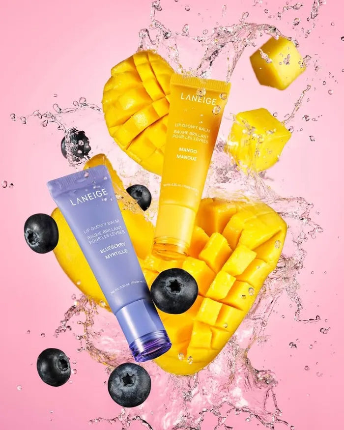 Laneige Lip Glowy Balm set in Mango and Blueberry with fresh fruit and water splashes on a pink background.