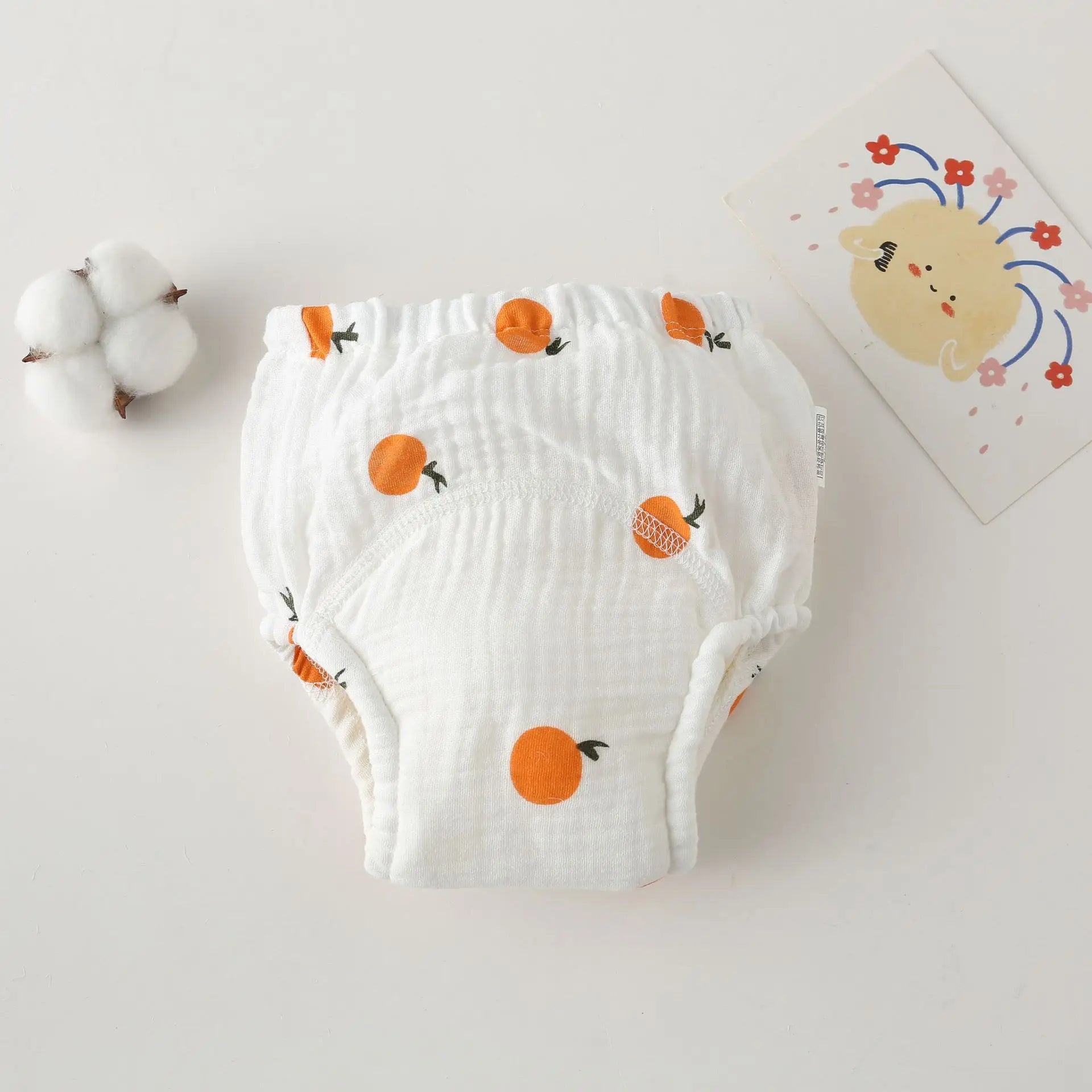 Reusable baby cloth diaper in white muslin with orange fruit print for baby care.