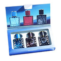 Three square glass cologne bottles in a gift set, featuring blue, red, and black colored glass and Medusa emblems.