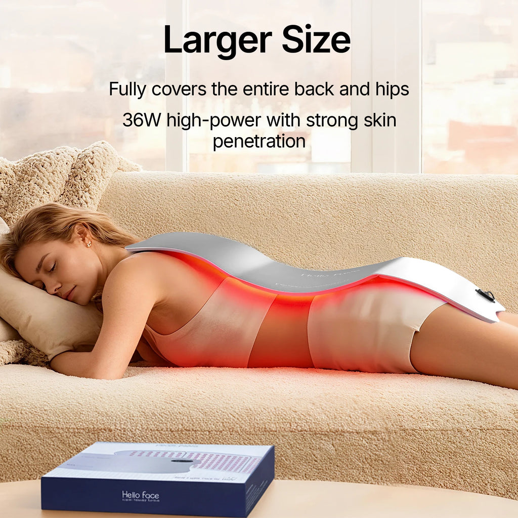 A woman lies on a couch with a large, flexible, silver Hello Face red light therapy mat covering her back.