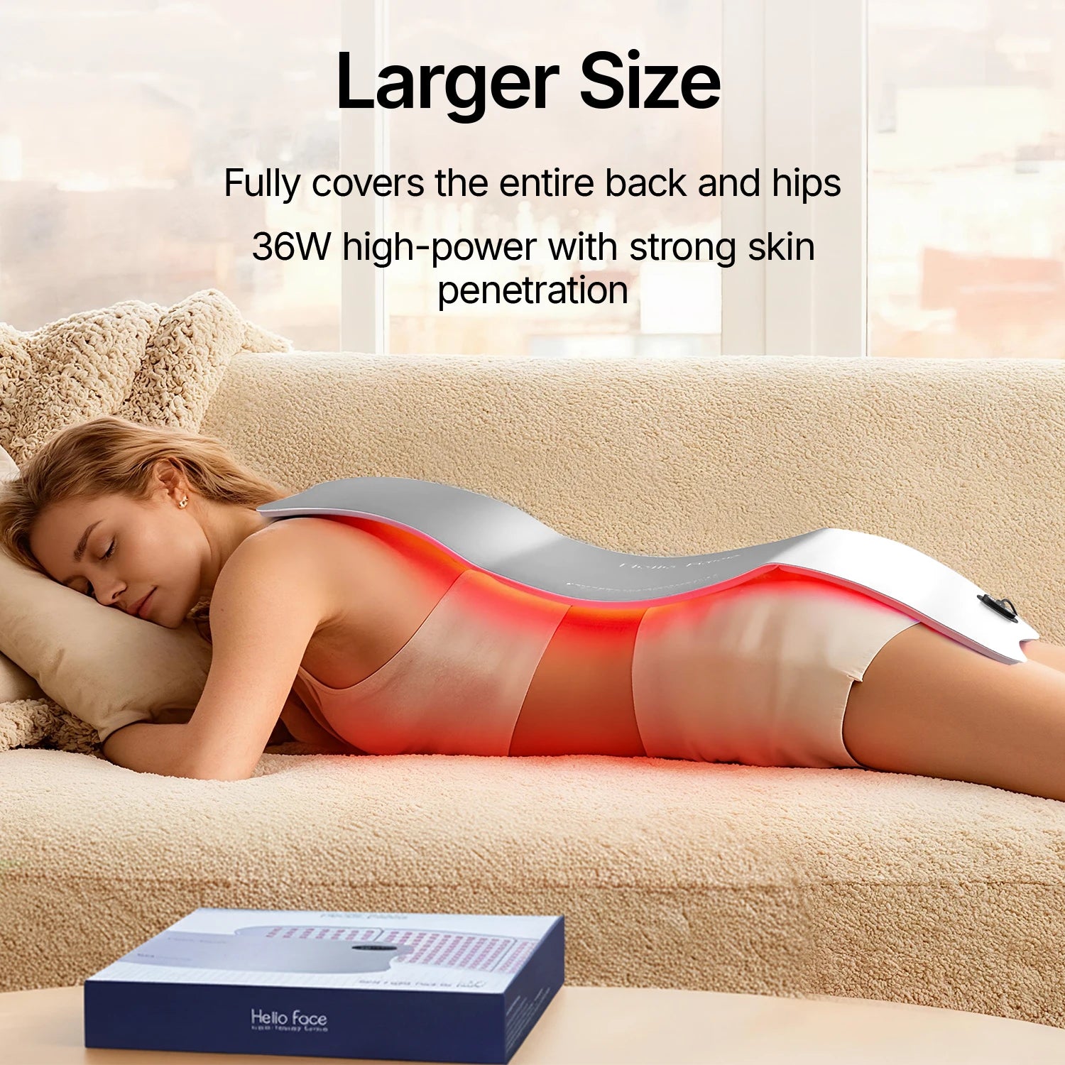 A woman lies on a couch with a large, flexible, silver Hello Face red light therapy mat covering her back.