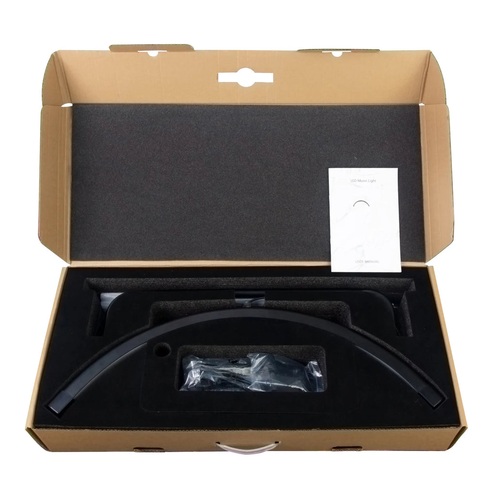 Black semi-circular LED moon light base and components in foam-lined cardboard packaging with a user manual.